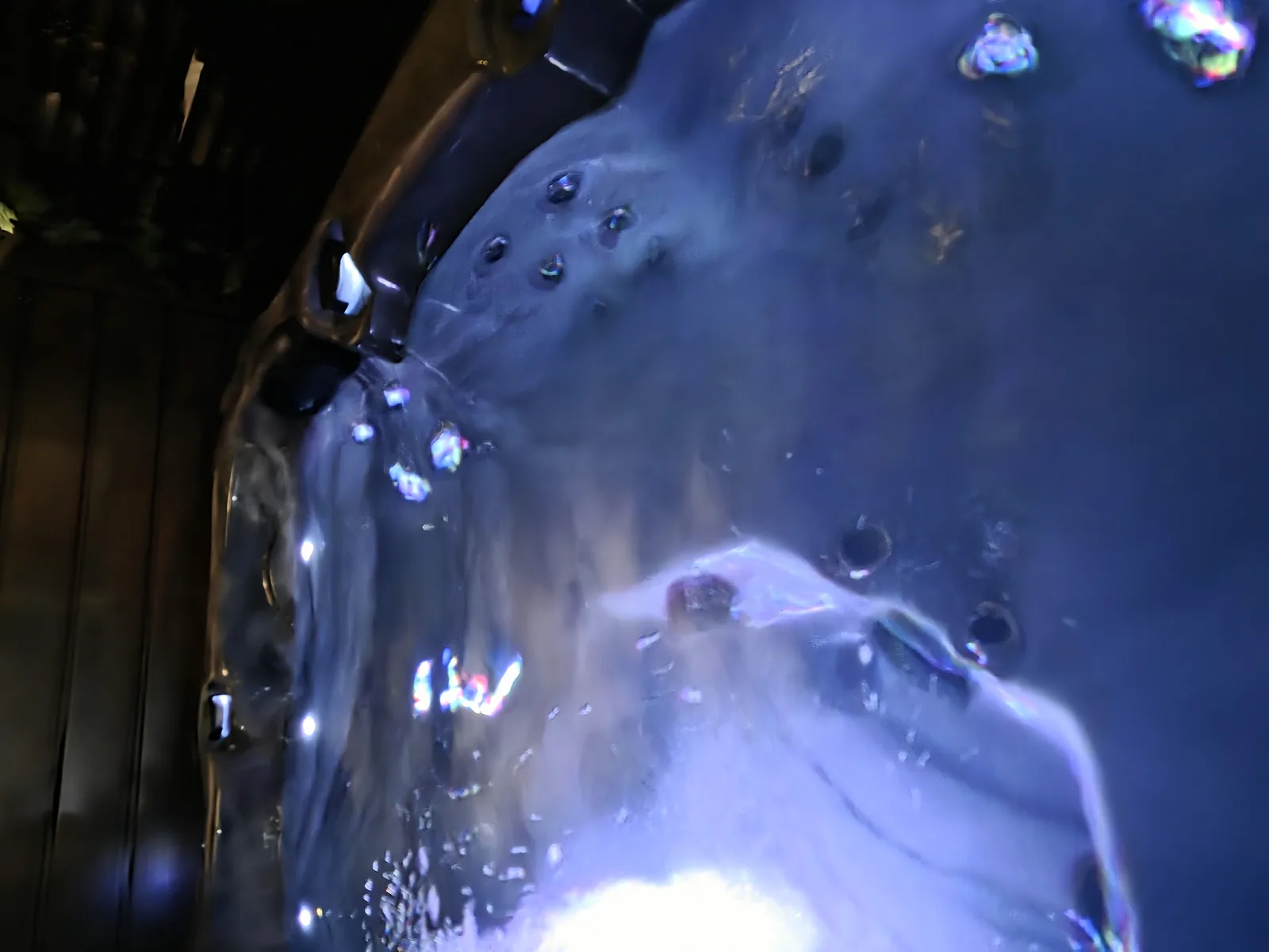 Gros plan sur l’eau bouillonnante d’un spa le soir, éclairée par les LED.